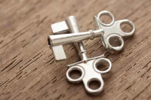 Two decorative small silver crossed cabinet keys lying on a wooden surface in a conceptual image