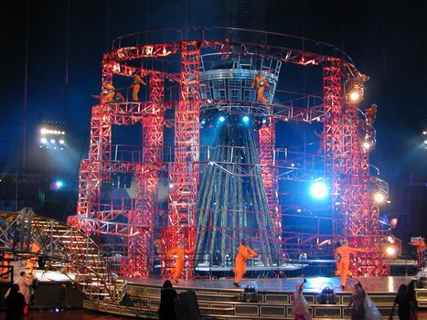 Acrobats performing in a circus show in a Big Top on a centre stage lit by spotlights