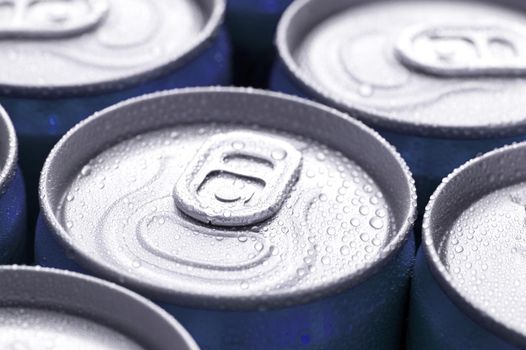 Canned drinks background wth a close up low angle view of the tops of the tins and pull tabs with water condensation from the cold