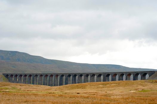 Panoramic view of the stone arches of the Ribblehead Viaduct, a curved stone Victorian railway viaduct crossing the River Ribble in North Yorkshire