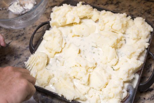 Thick creamy mashed potato pie topping viewed high angle on a granite kitchen counter