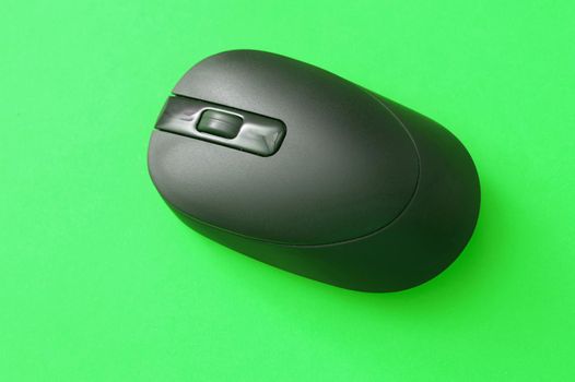 Close up Black Wireless Computer Mouse Isolated on Green Background, Emphasizing Copy Space.