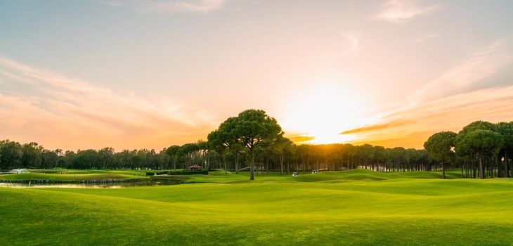 Golf course at sunset with beautiful sky. Scenic panoramic view of golf fairway