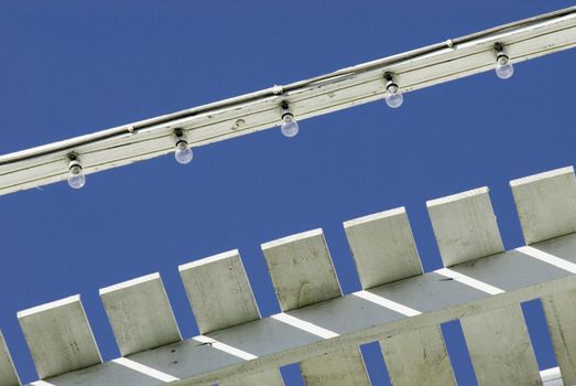 A close up of amusement park lighting during daytime with a blue sky background.