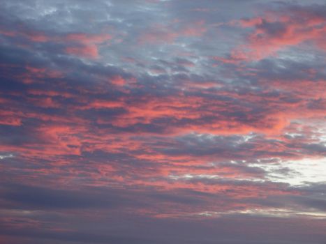 clouds glowing pink illuminated by the setting sun