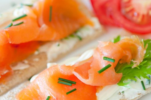 Delicous smoked salmon snack with thinly sliced fish on crispbread topped with fresh chives
