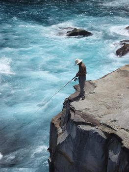 a man fishing from the top of a tall cliff