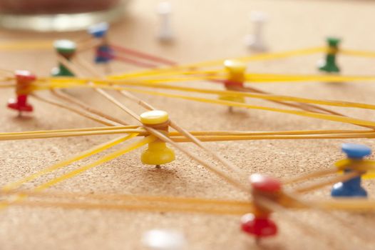 Team Concept - Close up Colored Pins on Cork Board Connected with Rubber bands