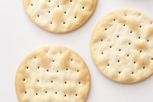Water crackers background with an overhead view of plain crispy water biscuits made from flour and water served to accompany a cheese platter, on white