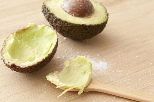 Close-up of cut fresh avocado and spoon on wooden table