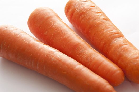 Trio of fresh raw carrots in a close up view for use as a healthy ingredient in salads and cooking, rich in carotene