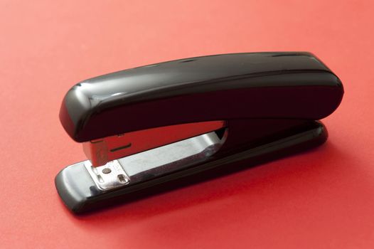 Close up Office Black Stapler Isolated on Red Background, Emphasizing Copy Space.