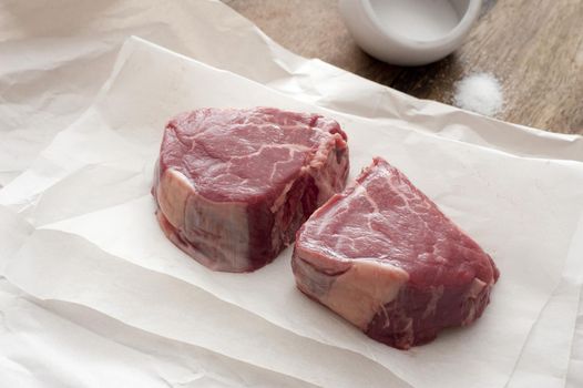 Close-up of two pieces of beefsteak on baking paper.