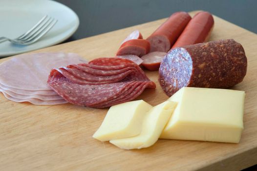 Protein rich German breakfast with sliced ham, salami and sausage and portions of cheese on a wooden platter