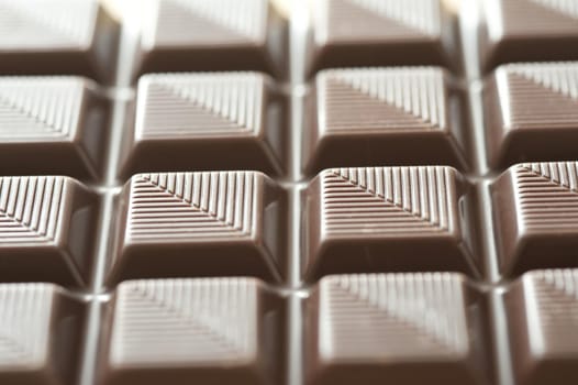 Textured bar of chocolate candy viewed at an oblique angle to emphasise the striped pattern, with selective focus
