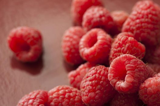 Close up of a vibrant pile of fresh picked red raspberries on a rustic background.