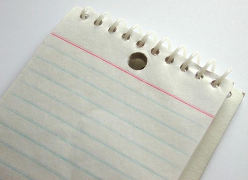 Blank spiral bound notepad with ruled lines on a white background, close up view of a portion of the pad