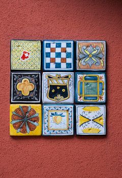 decorative glazed painted tiles on a terracotta coloured wall