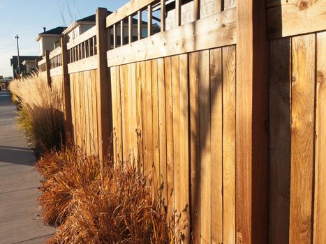 Wood fence next to the sidewalk in residential neighborhood.