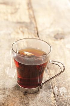 Close Up of Tea Bag Steeping in Glass Mug - Still Life of Fresh Brewed Black Tea in Glass on Rustic Wooden Table