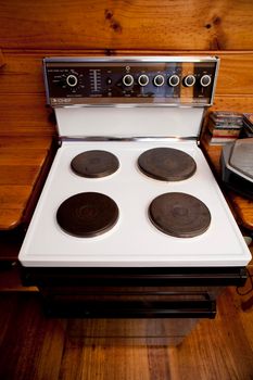Modern domestic freestanding stove with four solid hot plates in a wooden kitchen for cooking food and household meals