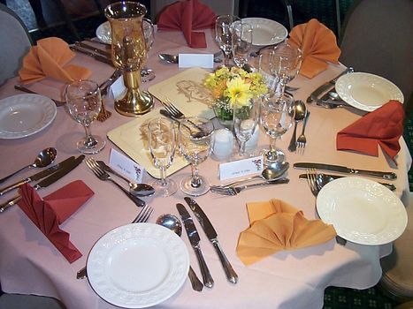 Formal dinner table at a catered event with elegant linen and silverware with name tags and place settings