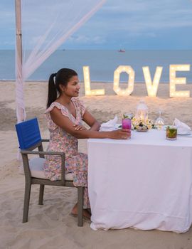 Romantic dinner on the beach of Huahin Thailand, dinner by candle light in Hua Hin , Valentine's concept. Asian women having dinner on the beach during sunset