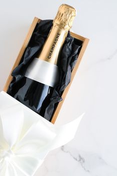 Wedding celebration, lifestyle and luxury present concept - A champagne bottle and a gift box on marble