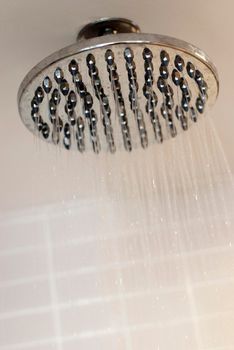 Water droplets falling from a modern shower head while enjoying a nice refreshing shower