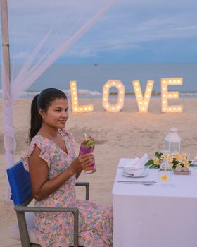 Romantic dinner on the beach of Huahin Thailand, dinner by candle light in Hua Hin , Valentine's concept. Asian women having dinner on the beach during sunset