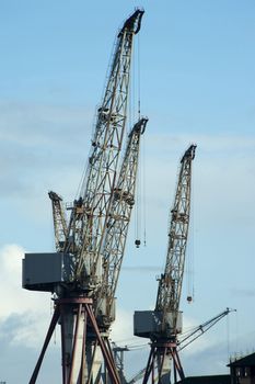 Large industrial cranes on the Clyde boatyards in Glasgow Scotland silhouetted against a sunny blue sky