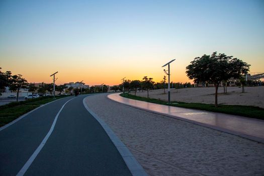 Jogging and cycling tracks in Al Warqa park, Dubai, UAE in the evening. Lamp post powered by solar panels can be seen in the picture.