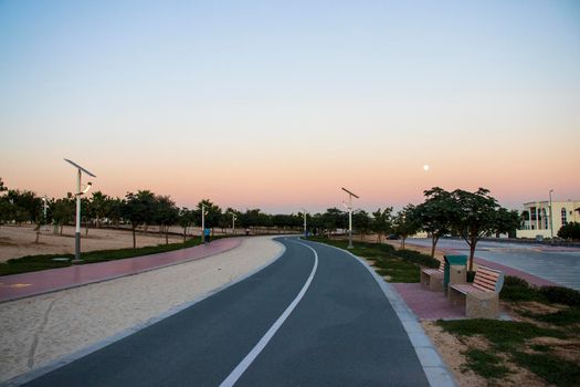 Jogging and cycling tracks in Al Warqa park, Dubai, UAE in the evening. Lamp post powered by solar panels can be seen in the picture.