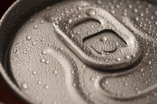 Ice cold beverage in a can with a closeup view of the unopened pull tab on the lid with condensed water droplets