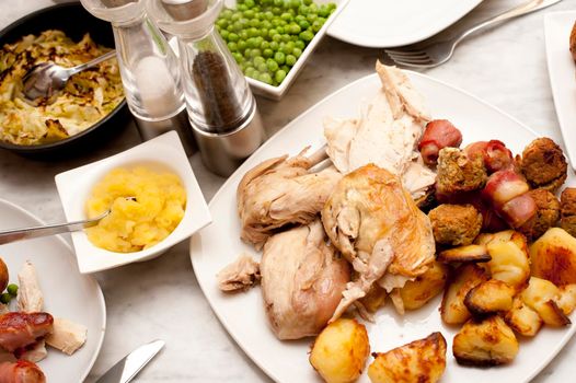 Serving of a roast dinner on a dining table with meat, vegetables, sauce and condiments for a delicious wholesome meal