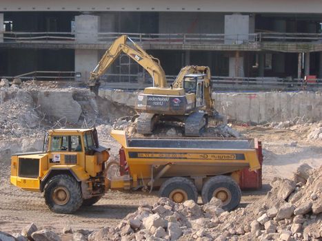 An industrial excavator and dump truck excavating and clearing rubble at a construction site