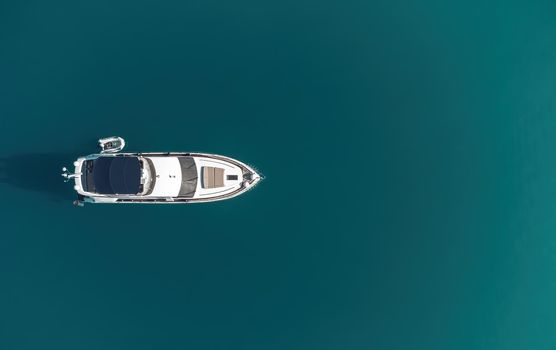 Aerial boat race. Luxury cruise trip. View from above of white boat on deep blue water. Aerial view of rich yacht sailing sea. Motor boat racing wave. Summer journey on luxury ship