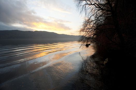 Beautiful tranquil sunset in the English Lake District with a delicate glow in the sky reflected in the calm water of the lake below