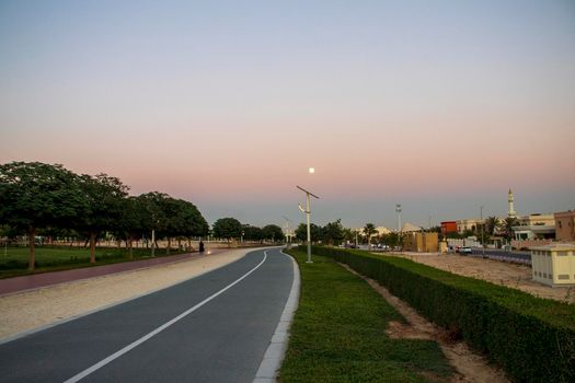 Jogging and cycling tracks in Al Warqa park, Dubai, UAE in the evening. Lamp post powered by solar panels can be seen in the picture.