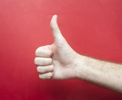 Close up Conceptual Human Hand Showing Thumbs-up on Red Gradient Background