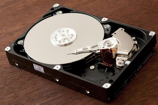 Open hard disk drive HDD close-up over dark wooden background