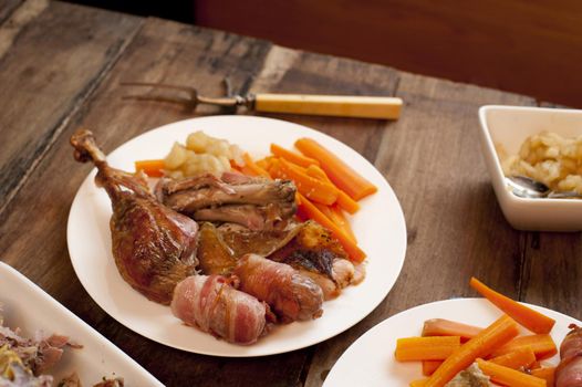 A rustic dinner table setting with roast turkey and vegetables.