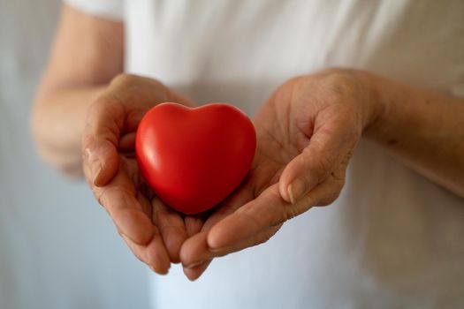 Hands holding red heart, healthcare, love, organ donation, mindfulness, wellbeing, family insurance and CSR concept, world heart day, world health day, national organ donor day.