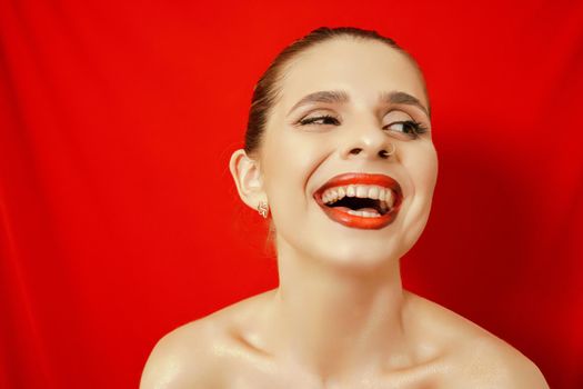 Portrait of a smiling beautiful young woman. Red background. Studio shot