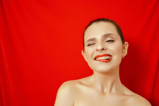 Portrait of a smiling beautiful young woman. Red background. Studio shot