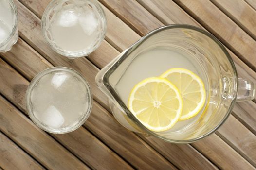 Homemade fresh healthy lemonade served in a jug and glasses on a slatted wooden picnic table for a refreshing summer dink, overhead view