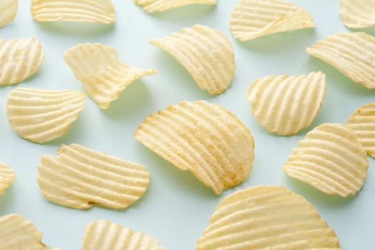 Group of separate full sized crispy ridged potato chips as background about snack food over blue