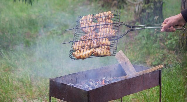 fry chicken skewers on the grill. Picnic in nature. selective focus