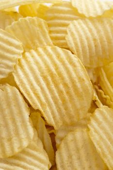 Close up on full frame view of ridged yellow potato chips with copy space for background about food and snacking
