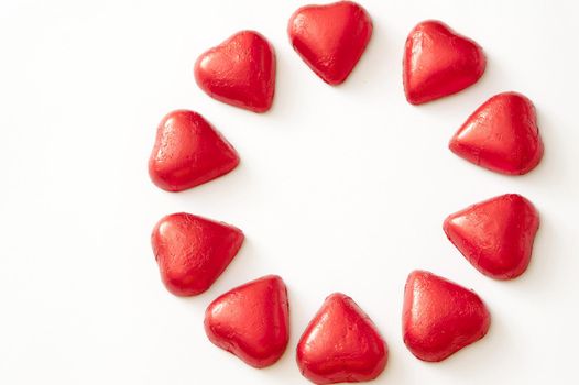 Circle of red Valentines hearts arranged on white with copy space in the centre and to the side conceptual of love and romance